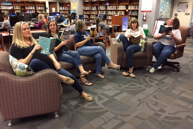 Teachers sitting in library furniture reading books