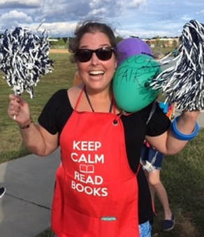 woman outside cheering, wearing red apron with text: keep calm and read books